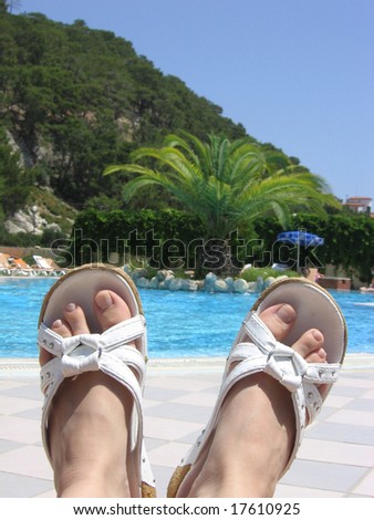 feet with beach shoes near the pool