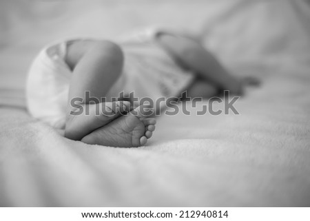 Cute feet of newborn baby sleeping on the bed