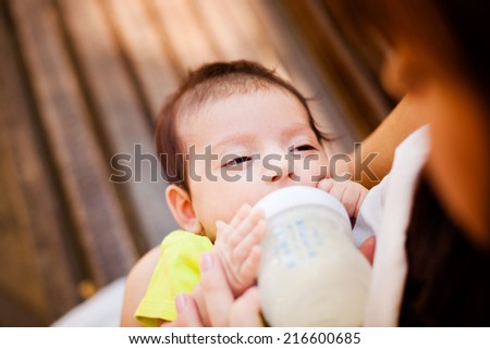 The image of the woman feeding her newborn baby from a children's small bottle
