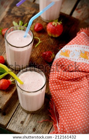Healthy nutritious tropical smoothie with strawberries blended with yoghurt or ice cream on a rustic wooden table top