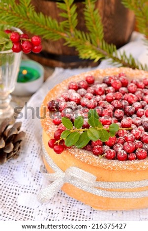 homemade cake with cranberries on a white tablecloth with candles and wine glasses