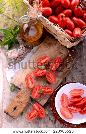 bullet tomatoes on cutting wooden board with pink salt and vegetable oil in a carafe