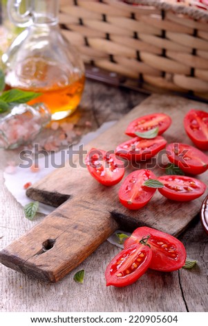 bullet tomatoes on cutting wooden board with pink salt and vegetable oil in a carafe
