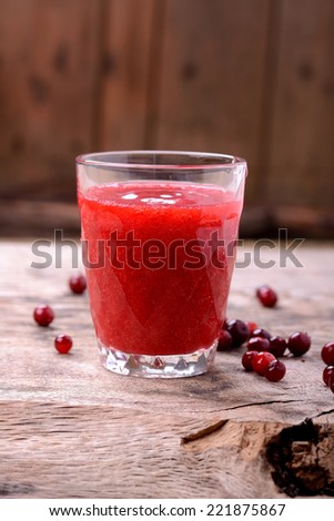 Red berry juice and cowberry on old wooden table. selective focus