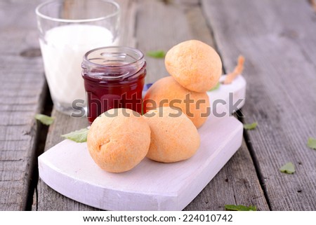 breakfast rolls with strawberry jam on a white cutting board on a wooden background