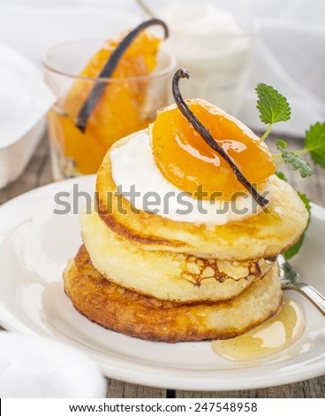Pancakes with yoghurt and apricots for breakfast on wooden background with a white cloth decorated with vanilla bean