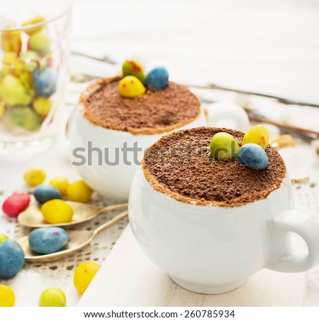 Easter cream dessert tiramisu based in portioned cups are decorated sweet candy in the form of eggs. Selective focus.