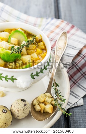 Homemade soup with brussels sprouts and croutons in white bowl decorated with a sprig of thyme. selective Focus