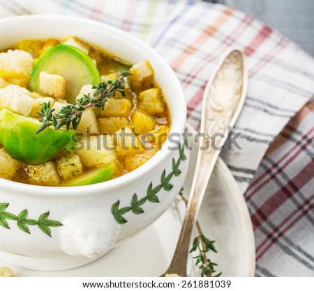 Homemade soup with brussels sprouts and croutons in white bowl decorated with a sprig of thyme. selective Focus