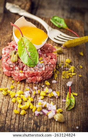 Close up of beef tartar with capers gherkins, onions, and egg yolk. Selective fodus