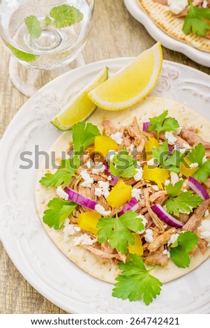 Tacos for lunch with chicken, pineapple salsa, purple onion and cilantro on porcelain plates and wooden background. Served with a glass of water with mint and lemon. selective Focus