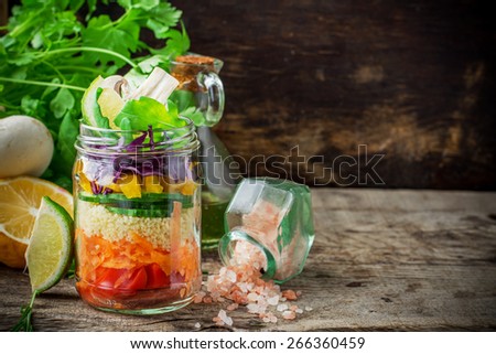 Bright rainbow salad  of tomatoes, carrots, pepper, red cabbage, arugula and mushrooms with butter and sea salt on a pink background vegetables and herbs. Trends in healthy eating. Selective focus.