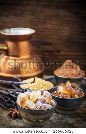 Golden caramel brown sugar crystals, vanilla pods, cocoa powder in a metal cup on vintage wooden background. selective Focus
