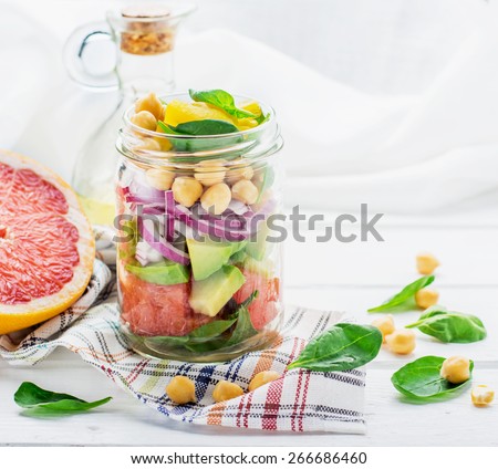 Fresh spring salad of grapefruit, avocado, sweet onion, spinach and chickpeas in a glass jar for a snack with you. The concept of healthy proper nutrition for the whole family. selective Focus