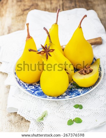 Sweet fragrant pears poached with saffron and spices. Served on a wooden background. Selective soft focus