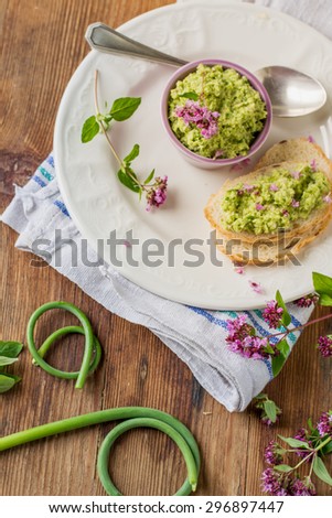 Green sauce with garlic arrows, oil, nuts and spices in a bowl with a sprig of oregano. selective Focus