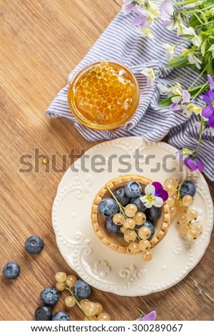 Tartlets of pastry with blueberries and currants with fresh honey honeycombs on a wooden background. selective Focus