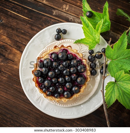 Delicious crispy tarts with black currants on wooden table, closeup