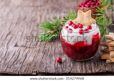 Dessert with cranberry sauce and sour cream decorated gingerbread cookies in the shape of stars and fresh berries cranberries in glasses on dark wooden background. selective Focus