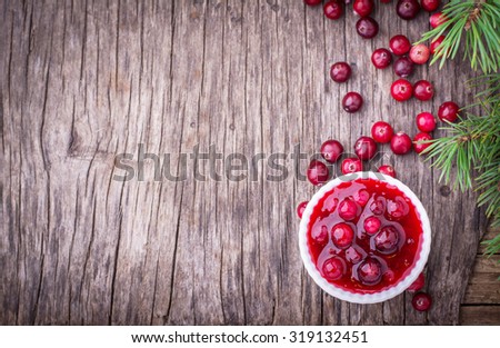 sauce of wild organic cranberries on a wooden table with berries and pine branches on a live cut down a tree