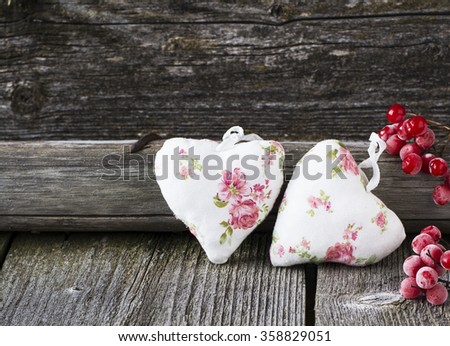 Two textile hearts with romantic flower coloring in simple dark wooden background with berries of red viburnum. selective Focus
