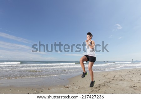 young woman with short hair running on the beach in a sunny day