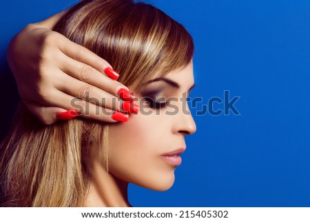 Beautiful woman with long bright hair and red nails. Glam make-up