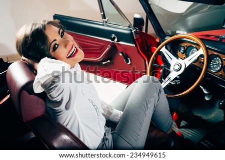 Smiling vintage woman in old red car