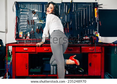 Beautiful young woman posing in vintage car repair shop