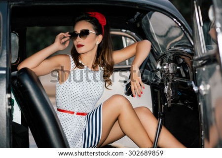 Beautiful pin-up girl inside vintage car