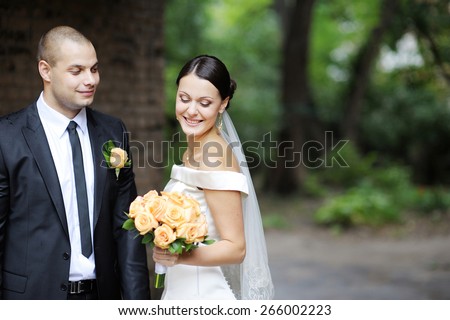 wedding, bride and groom standing in the rain on a background of green trees and road