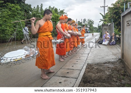 CHIANGMAI, THAILAND 29 July 2015 : Every day very early in the morning, the monks walk in the field to beg give food offerings to a Buddhist monk on July 29,2015 in Maechaem, Chiangmai, Thailand