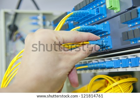 telecom engineer poses on fiber optical network cables patch panel