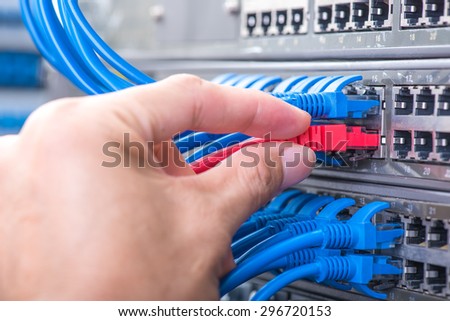 hand with network cables connected to servers in a datacenter