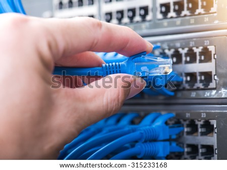 hand with network cables connected to servers in a datacenter