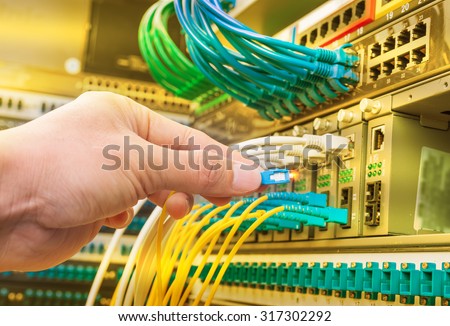 man connecting network cables to switches