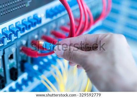 hand with fiber network cables connected to servers in a datacenter