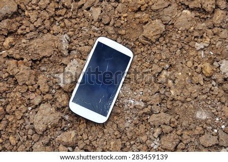 White Broken Cell Phone On Soil Surface.