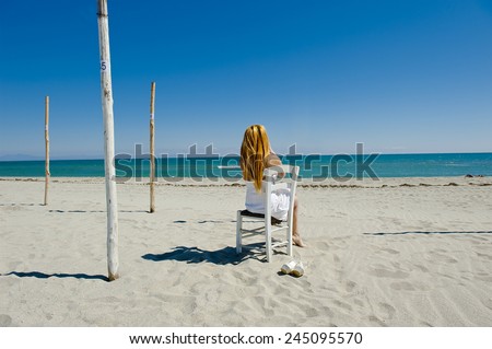 woman with long golden hair in a white dress sits on a chair and looks forward the deep sea for her captain