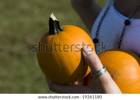 Color photograph of a small orange pumpkin being held by female model.