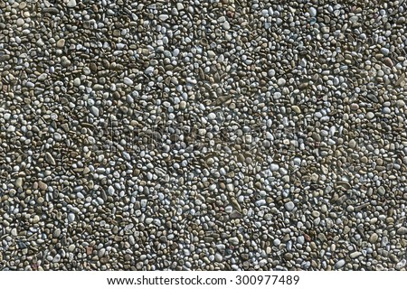 Exposed aggregate concrete with gray pebbles in closeup, taken at an older facade of the 80s