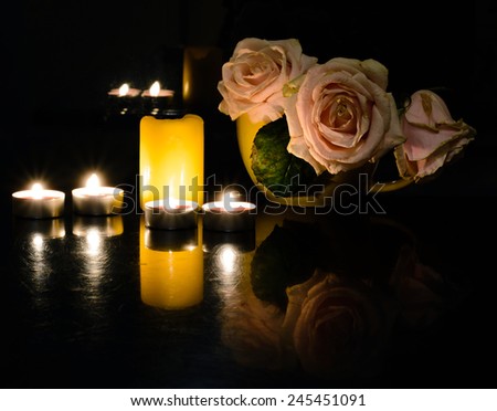 An arrangement of scented candles on the table in the evening for dinner and flowers. Romantic dinner for Valentine\'s day.