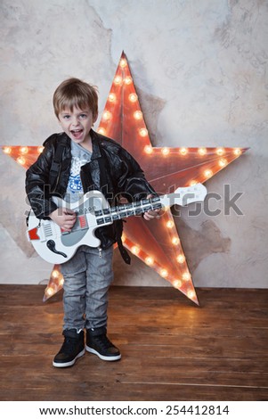 little cute boy playing guitar and smiling like a rock-star