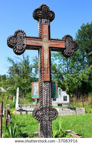 Old wooden painted cross, depicting Jesus Christ crucified. Situated in the graveyard of the old wooden church in Salistea de Sus, Maramures, Romania