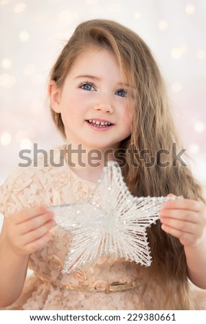 Close-up portrait of a little girl on Christmas day with a star in hands. Preparing for Christmas.