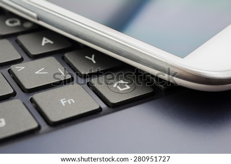 A White Mobile On A Keyboard With Home Button