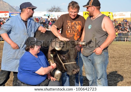 LEYTRON, SWITZERLAND - MARCH 25: the winning cow Lilas with the Defayes family owners, at the cow fighting championships. March 25, 2012 in Leytron, Switzerland