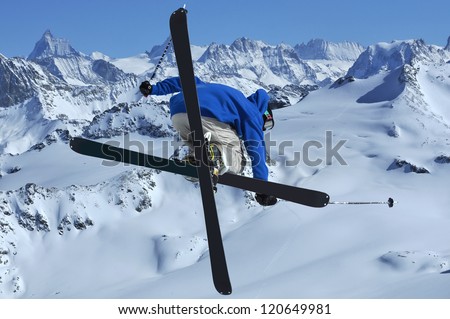 A freestyle skier jumping in the high mountains with crossed skis