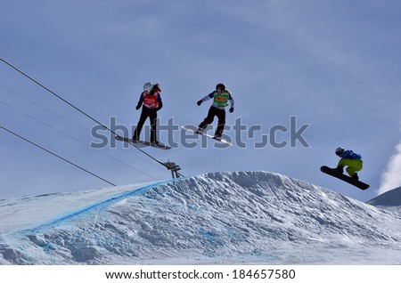 VEYSONNAZ, SWITZERLAND - MARCH 11: women competitors on a high jump in the Snowboard Cross World Cup: March 11, 2014 in Veysonnaz, Switzerland