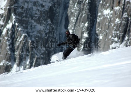 Snowboarder on the Mt Blanc with the north face of the Tacul behind him